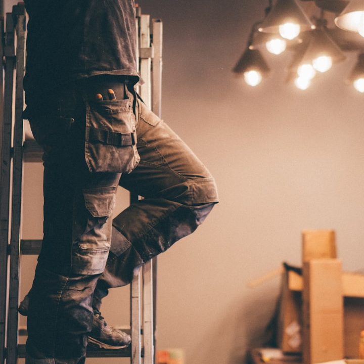 Electrical Work A hand wearing a glove uses a screwdriver on electrical wires in a wall socket.